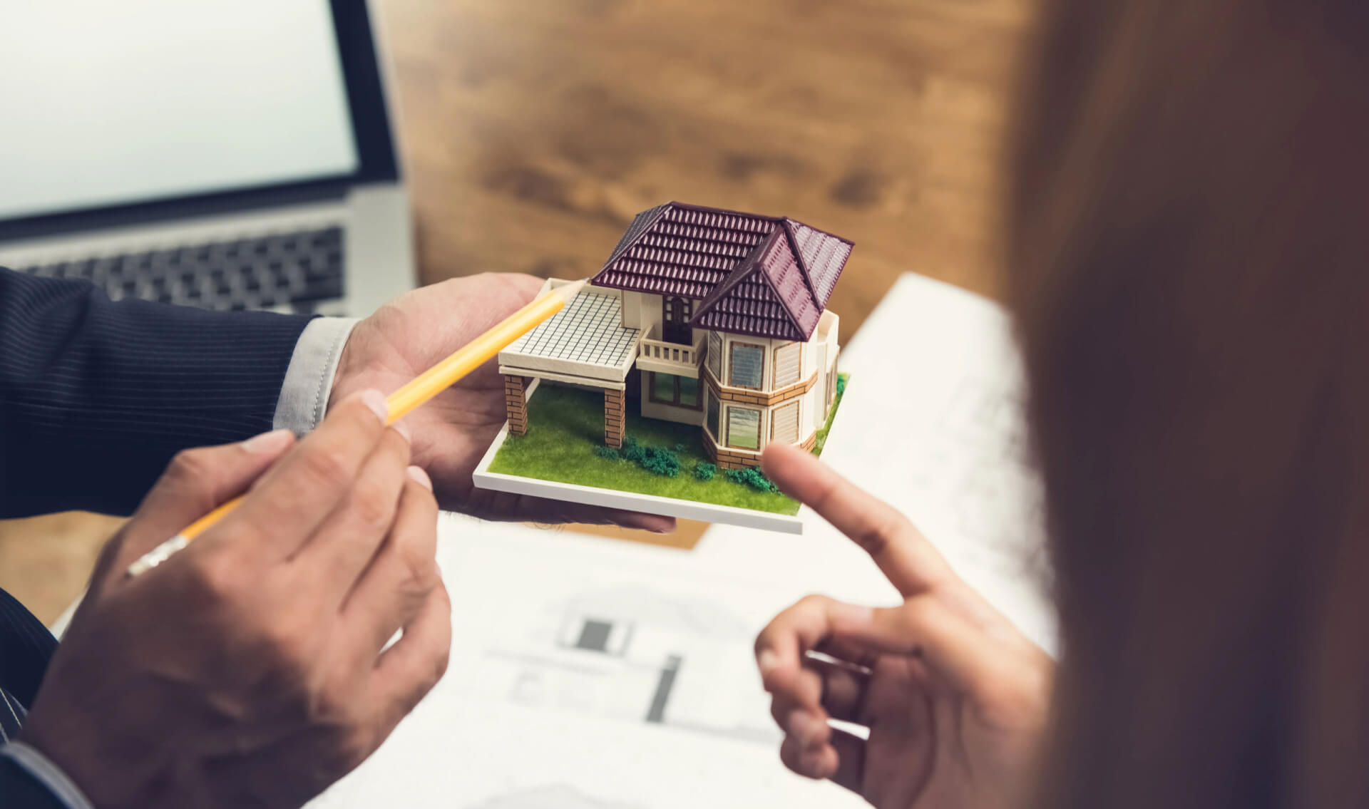 Housing developer agent holding an architectural model and explaining concept to client or architect for real estate development.